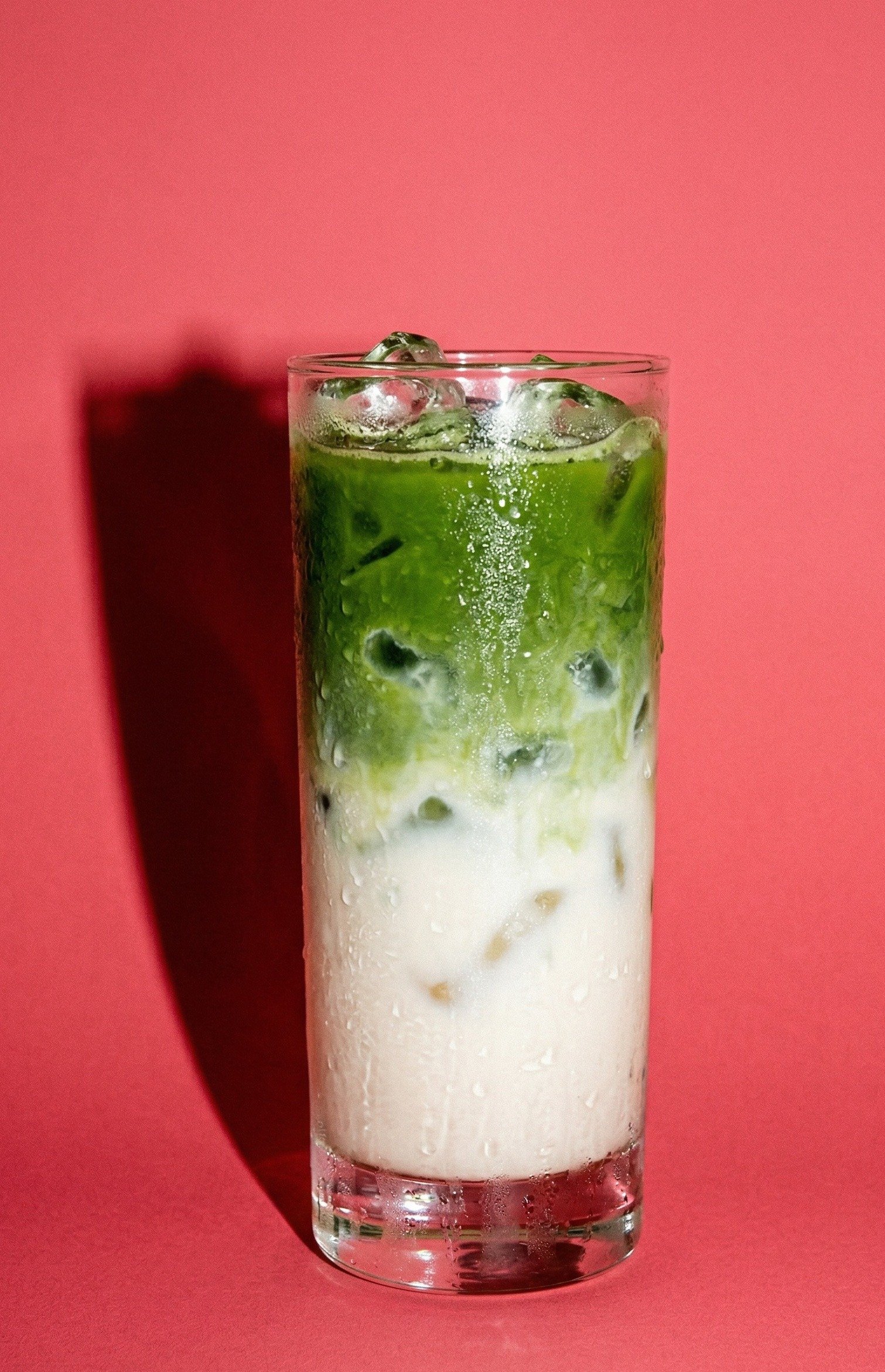 Classic Iced Matcha Latte — layered green matcha floating over oat milk with ice in a tall glass